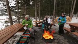 Family relaxing around fire pit on snowy patio Stock Footage