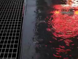 rain on sidewalk with grate and reflected neon light Stock Footage