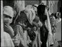 1951: CASABLANCA, MOROCCO: CLINIC: EXT Clinic w/ Moroccan people standing in line, some w/ children. CU Moroccan male w/ swolen eye area, trachoma, eye disease. INT Clinic w/ doctors, nurses treating male & female patents for trachoma, washing eyes. Instructional Video