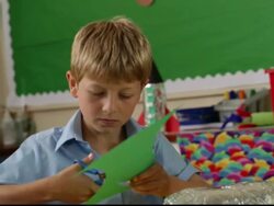 MS Boy sitting in classroom cutting construction paper with scissors / Great Yarmouth, England, United Kingdom Stock Footage