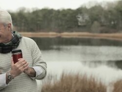 Mature couple by lake, talking and holding drinks flasks Stock Footage