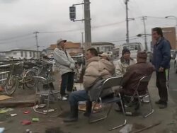 Destruction caused by tsunami after magnitude 9 Tohoku earthquake, north east Japan, March 2011. Drive past survivors sitting on street in Ishinomaki after tsunami Stock Footage