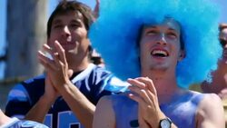 MS Football fan wearing wig and body paint standing and cheering with crowd during game Stock Footage