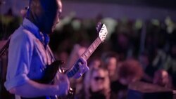 Masked man plays guitar with rock band to enthusiastic crowd at outdoor music festival Stock Footage
