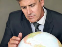 Mature business man with a world globe against gray background Stock Footage