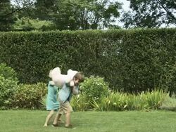 Boy and girl in garden fighting over toy, girl snatches it and runs away Stock Footage