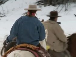 TS Horses trotting in snow being herded by cowboy and cowgirl / Shell, Wyoming, United States Stock Footage
