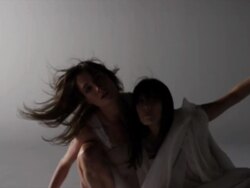 two woman draped with silk around them crouching together reaching towards camera Stock Footage
