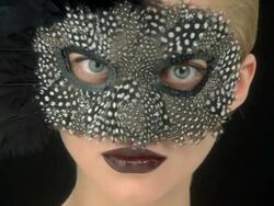 Close up of young woman in a feather mask turning to camera Stock Footage