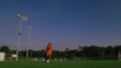 A soccer player runs along a field while kicking a ball. Stock Footage