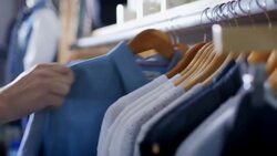 Customer hangs shirt back on rack in modern clothing store Stock Footage
