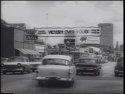 B/W 1962 "Victory Over Polio" banner over town street with traffic / Texas / newsreel Stock Footage
