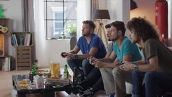 Guys sitting on couch playing video games and cheering Stock Footage