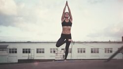 Young woman doing yoga outdoors on a rooftop at sunset Stock Footage