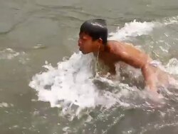 MS TS SLO MO Shot of boy under water in river then emerging smiling and disappearing with strong current / Ou river, Luang Prabang, Laos Stock Footage