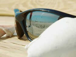 Sunglasses in foreground shells on bench reflection of person Stock Footage