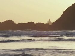 WS SLO MO View of lighthouse is silhouette against rocky Pacific coast as waves pounds and at sunset and seagulls fly by / Astoria, Oregon, United States  Stock Footage