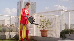 Superhero watering potted plant on city rooftop Stock Footage