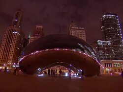 MS PAN  Shiny, stainless steel sculpture cloud gate at at&t Plaza and surrounding skyscrapers at night / Chicago, Illinois, United States Stock Footage