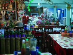 MS Bar area of small restaurant with ecclectic mix of decorations including  miniature christmas tree and army helmet with different colored liquids bottles /  Vang Vieng, Vientiane, Laos Stock Footage