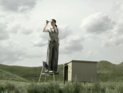 Woman standing on chair in a field by desk, using a telescope Stock Footage