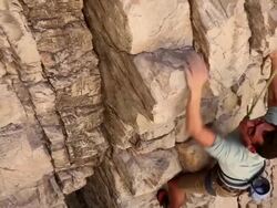 Handheld tilting shot of a rock climber making his way up a cliff. Stock Footage