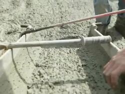 Concrete Flowing from Mixer Trough to Workers with Leveling Stock Footage