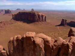 Aerial over 'Camel Butte' and 'Elephant Butte' rock formations / Monument Valley Stock Footage