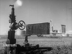 1952: CANADA: OIL INDUSTRY: HA XWS Remote refinery in valley w/ mountains distant BG. LA MS Release valve w/ city BG. Angled WS Tanks. BEHIND Man turning release valve w/ fire burning in distance, WS Large fireball rising in air. Instructional Video