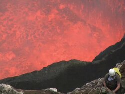 Climber stands on ledge above dangerously erupting lava, Marum Volcano, Ambrym Island, Vanuatu Stock Footage