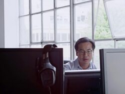 MS businessman sitting in office surrounded by computer monitors looking out windows Stock Footage