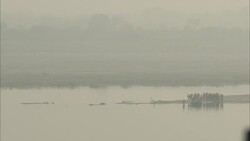 Celebrants on a promontory wait for a boatman to take them down river during a Hindu holiday. Stock Footage
