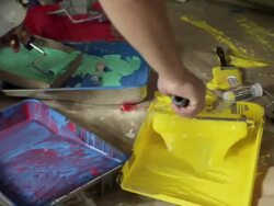 Close up of paint trays, man loading paint roller with yellow paint Stock Footage