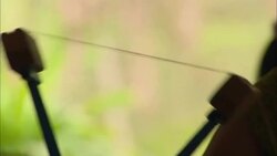 Hands turn a spoked wheel that pulls threads. Stock Footage