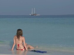 Woman sitting on beach in bikini, Vaavu Atoll, The Maldives Stock Footage