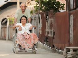 Senior man pushing her disabled wife on wheelchair Stock Footage