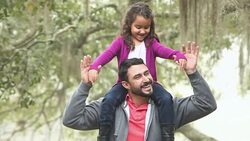 Little Hispanic girl sitting on father's shoulders Stock Footage