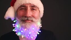 Senior adult man with a beard in a black T-shirt and Santa Claus hat looking at the camera shakes his head and fun Stock Footage