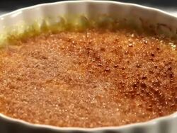 CU Butane torch caramelizing brown sugar coating layer on top of creme brulee custard in white ramekin and raspberries being put / Los Angeles, California, United States Stock Footage