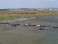Aerial traffic crossing Holy Island causeway at high tide / England Stock Footage