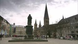 Pedestrians stroll through a plaza with a statue in the center in Frankfurt. Stock Footage
