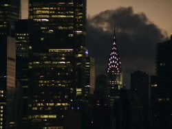 Static shot of the chrysler building and adjacent lit up sky scrapers as the sun goes up in the cloudy manhattan sky Stock Footage