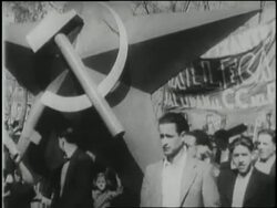 Demonstrators carry a large hammer and sickle statue; an image of Joseph Stalin covers the side of a truck. News Clip