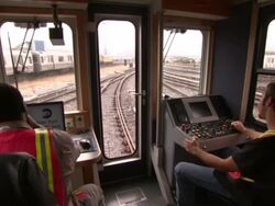 Train conductors operate a commuter train as they pass through the train yard. Stock Footage