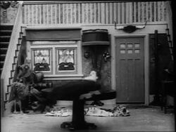 B/W 1916 Charlie Chaplin balancing on spinning table then losing balance + falling to floor Stock Footage