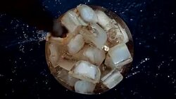 Pouring cola soda into glass of ice with splashes at slow motion Stock Footage