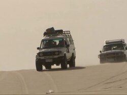 Medium, tracking-left - Two vehicles drive down a sand dune in the Sahara Desert in Egypt Stock Footage