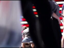 Out of focus pedestrians passing large American flag Stock Footage