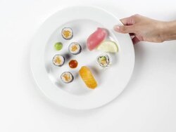 CU Woman hand entering setting down round white plate with sushi, nigiri, salmon, avocado, yellowtail salmon, shrimp and raw fish / Omaha, Nebraska, United States Stock Footage