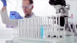 Scientist working behind test tube rack Stock Footage